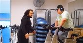A trainer encouraging a main on a stationary bike in a fitness room