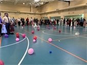 A crowd of parents with kids. Balloons litter the floor.