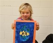 A girl holding up a painting and smiling