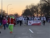 A green grinch leads a lacrosse team down the road during a holiday parade