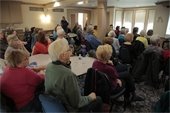 An audience sitting and listening to a lecture in a historical building