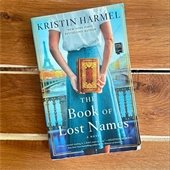 The cover for "The Book of Lost Names" featuring a woman holding a book