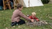 Two children playing with a rabbit with 19th-century tents in the background