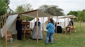 An era-accurate Civil War tent and reenactors with visitors asking questions