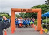 Runners standing at the finish line as a mascot high fives them.