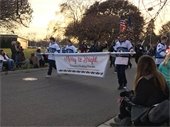 A marching band carrying a banner that says "Merry & Bright"