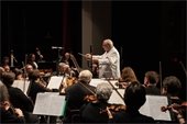 A man in white directing an orchestra