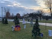 A Festive Forest of decorated holiday trees sit in the foreground of a sunset at Greenmead Historical Park.