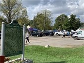 Sign for Greenmead Historical Park with crowd walking past