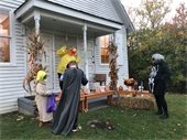 Adults and children in Halloween costumes in front of an old house