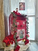 Santa's red mailbox adorned by poinsettia flowers as it awaits letters from children