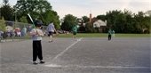 Kids playing baseball while a coach pitches the ball