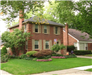 A Two Story House with Brightly Colored Flowers in the Front Lawn
