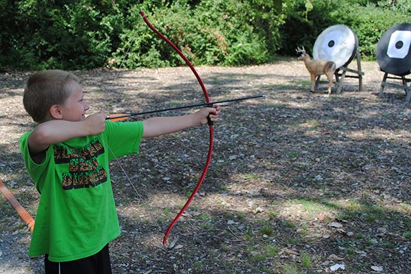 Young boy shooting an arrow at the target 